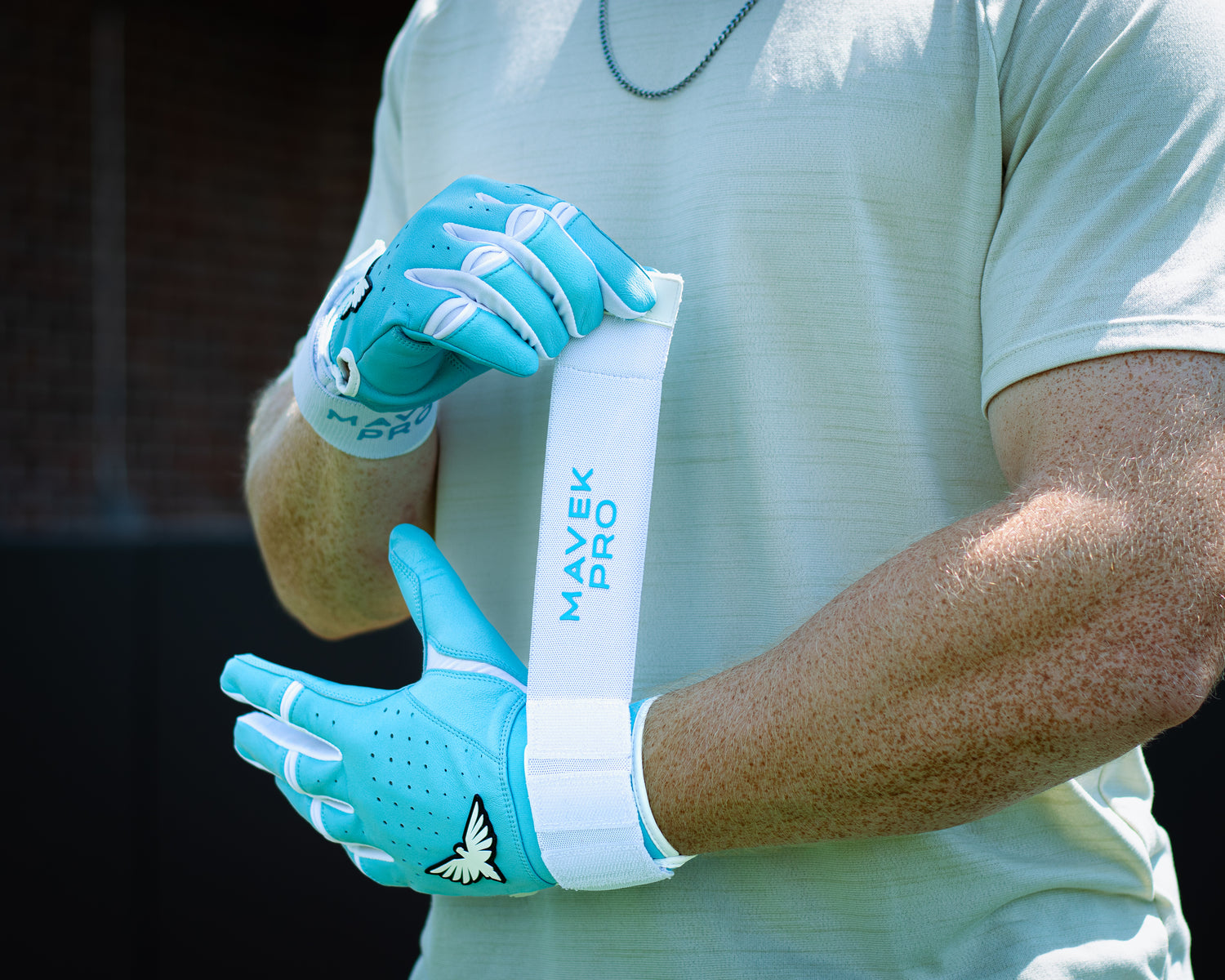 Person wearing blue gloves with a white strap labeled 'Mavek Pro' on a blurred background