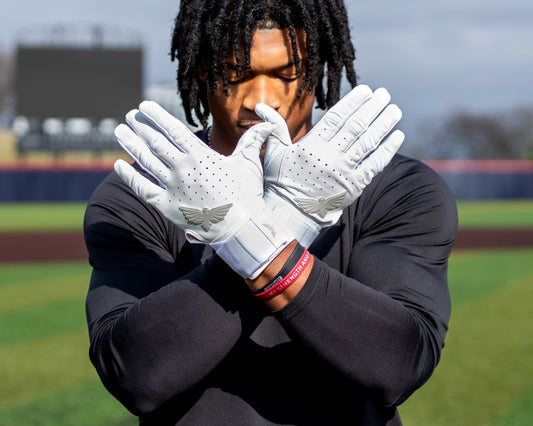 Person wearing white gloves with a logo on a sports field